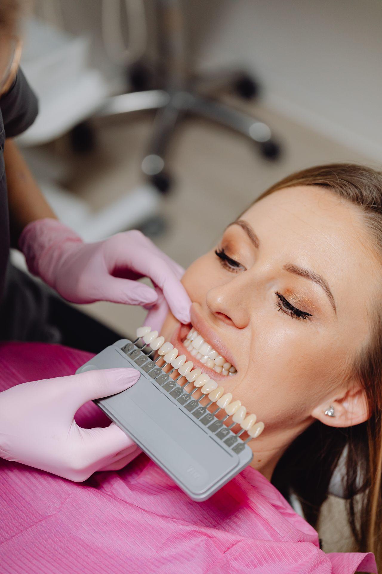 Dentist holding a shade guide in front of a patient