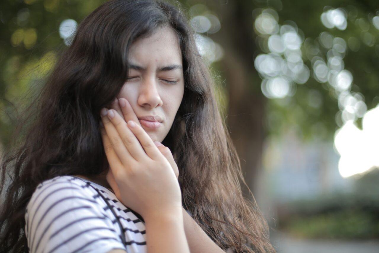 Young woman with severe tooth pain seeking dental emergency care in Tillsonburg